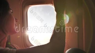 一个年轻的女孩打开飞机的窗帘，享受飞行。